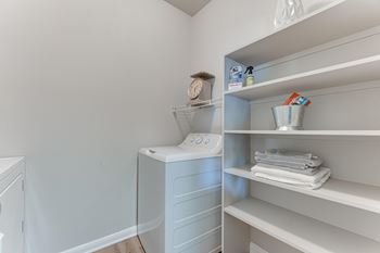 A white bathroom with a toilet and towel shelf at Limestone Ranch Apartments, Texas
